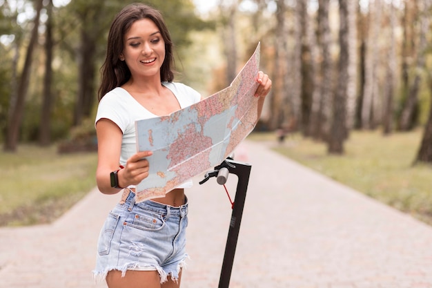 Smiley woman looking at map à côté de scooter électrique