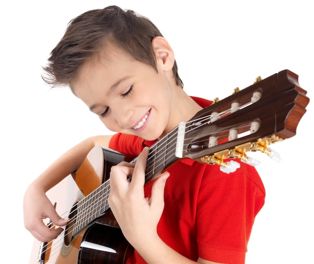 Smiling caucasian boy joue à la guitare acoustique - isolé sur un mur blanc