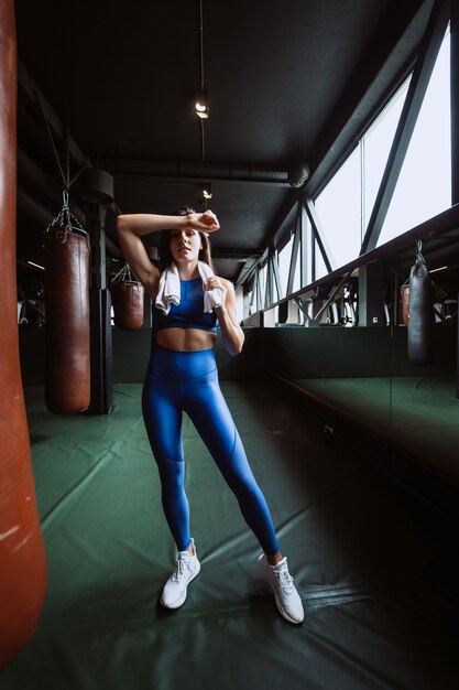 Smiling fit girl holding serviette et prendre du repos dans la salle de gym