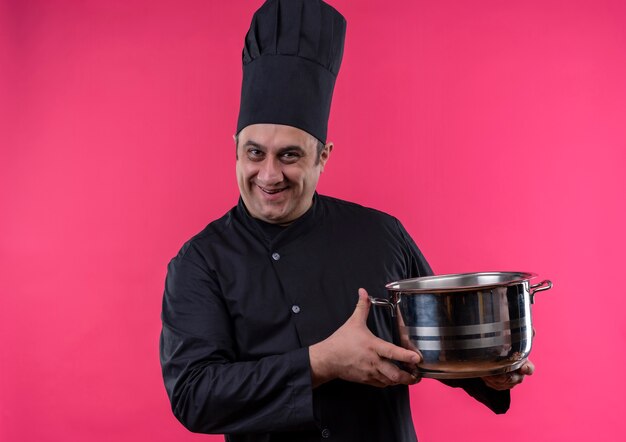 Smiling male d'âge moyen cuisinier en uniforme de chef tenant une casserole