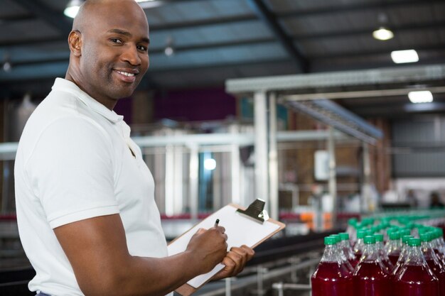 Smiling male worker notant sur les produits dans l'usine de jus