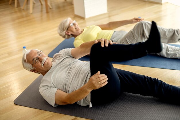 Smiling mature couple faisant des exercices de relaxation sur le sol à la maison