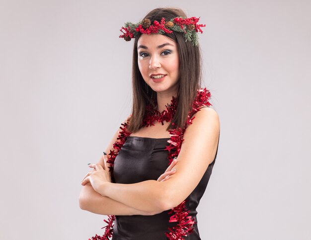 Smiling young pretty caucasian girl wearing Christmas head wreath et guirlande de guirlandes autour du cou debout avec posture fermée en vue de profil
