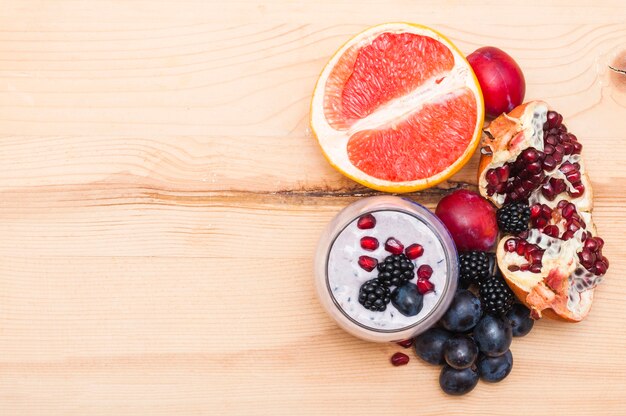 Smoothie aux pamplemousses coupées en deux; prune; les raisins; mûres et grenade, bois, toile de fond