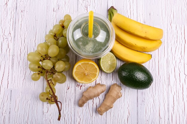 Le smoothie vert aux bananes, la citron vert, le raisin et l&#39;avocat se trouvent sur la table