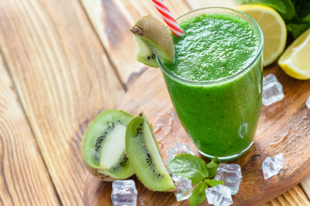 Smoothie vert aux fruits et légumes sur une table en bois