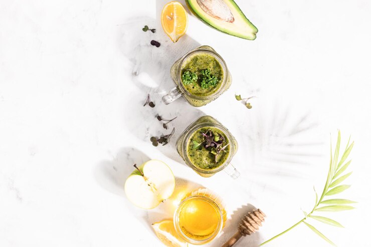 Smoothie vert detox - avocat, microgreen, citron et miel sur fond de pierre blanche ou de béton. Éclairage dur et ombre. Mise au point sélective, espace de copie. Vue de dessus.