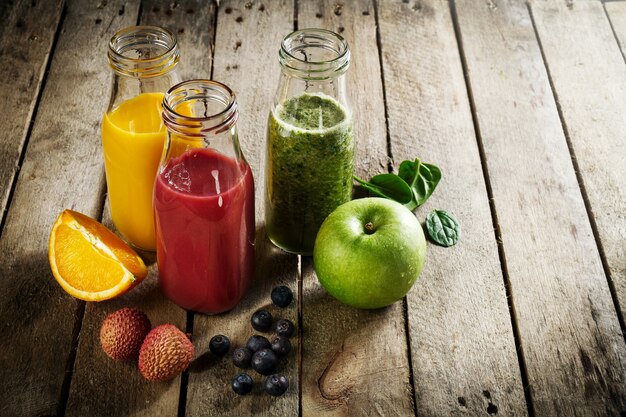 Des smoothies faits maison colorés délicieux et colorés dans des pots en verre sur une table en bois. Concept sain et désintoxiqué.