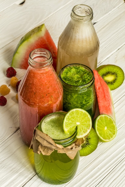 Photo gratuite smoothies verts et rouges dans un pot avec citron vert, kiwi