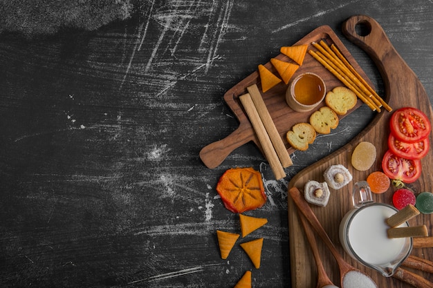 Snack board avec chips, craquelins et pâtisseries sur le plateau en bois