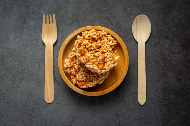 Snack thaï; KAO TAN ou cracker de riz dans un bol en bois avec une cuillère et une fourchette en bois