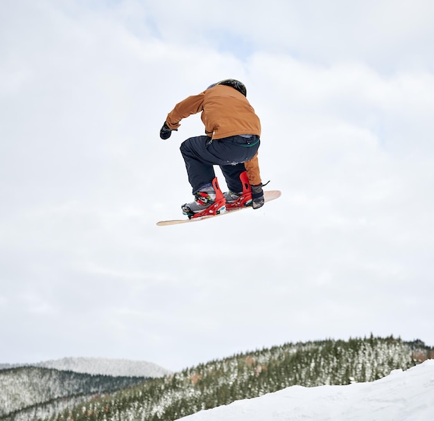 Snowboarder masculin faisant des tours dans l'air à la station de ski