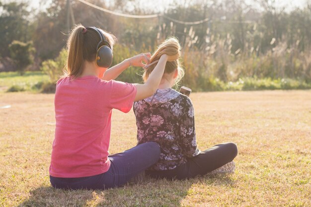 Sœur portant un casque attachant ses cheveux de soeurs dans le parc