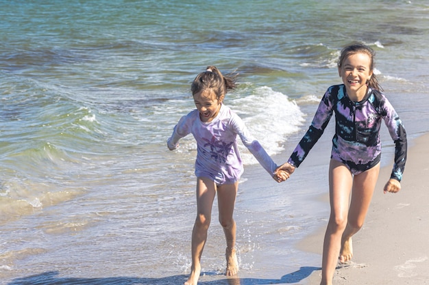 Les soeurs gaies de petites filles jouent sur le bord de la mer