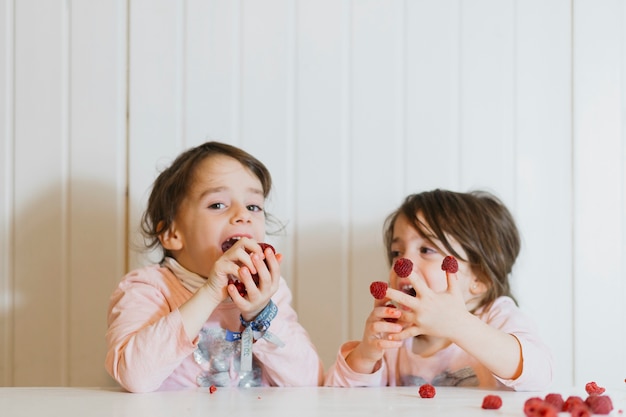 Photo gratuite sœurs mignonnes mangeant framboise