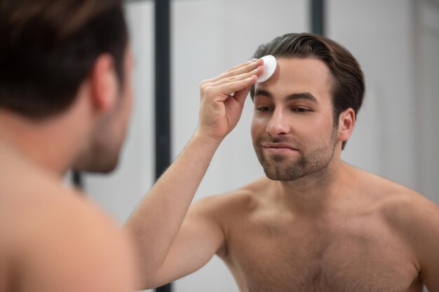 Soins du visage. Bel homme nettoyant son visage avec une éponge