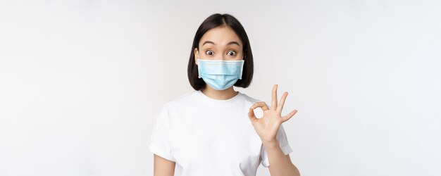 Les soins de santé et le concept médical de Covid ont impressionné une femme asiatique portant un masque médical qui a l'air étonnée et qui se montre