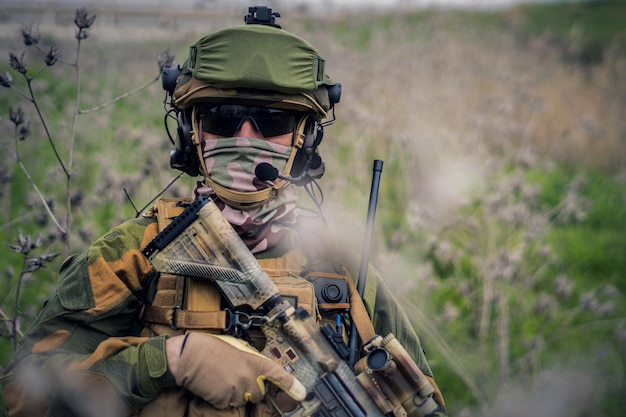 Soldat entièrement équipé dans l'uniforme de camouflage tenant un fusil d'assaut