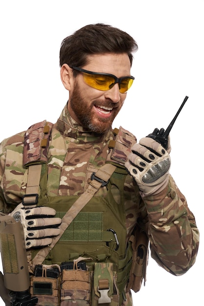 Photo gratuite soldat excité en gilet blindé parlant sur un talkie-walkie à l'aide de la radio