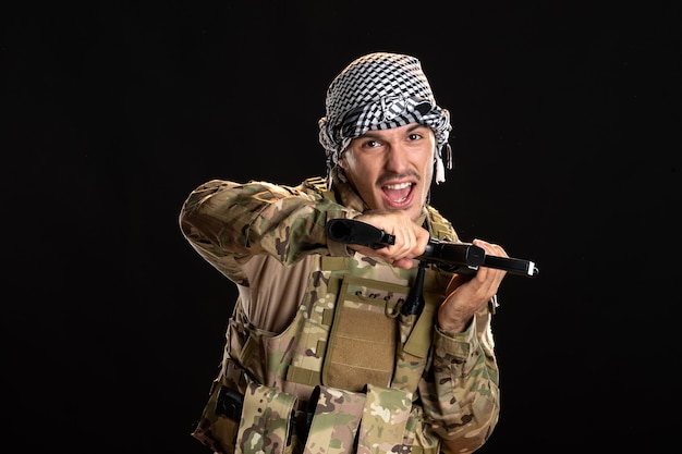 Photo gratuite soldat palestinien en tenue de camouflage avec mitrailleuse sur mur noir