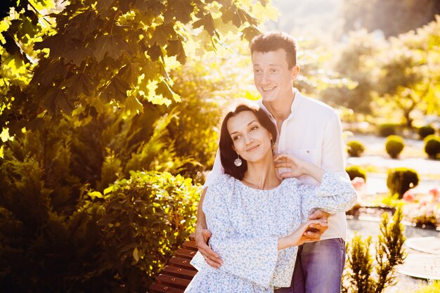 Soleil brille sur couple rêveur, étreindre sur un banc en bois dans le jardin