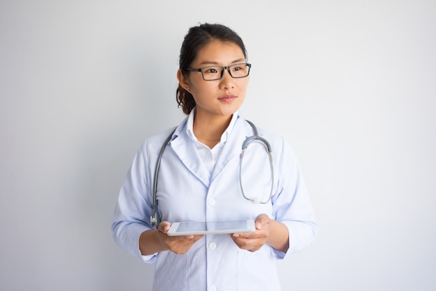 Songeuse jeune femme asiatique à l&#39;aide d&#39;une tablette tactile.