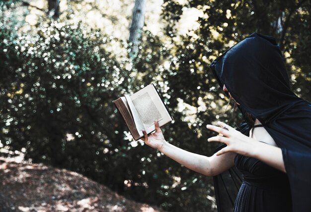 Sorcière utilisant le tome magique dans le fourré ensoleillé