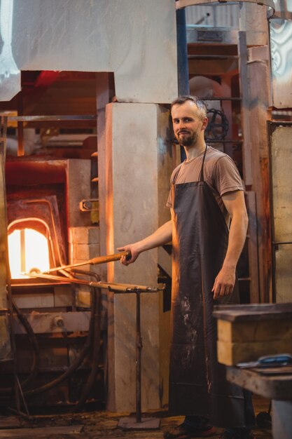 Souffleur de verre chauffant un verre dans un four de souffleurs de verre