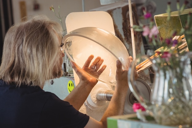 Souffleur de verre polissant et rectifiant une verrerie