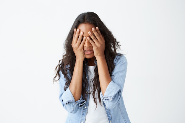 A souligné une femme afro-américaine aux longs cheveux ondulés décontractée, se sentant bouleversée, gardant les mains sur la tête, cachant son visage de désespoir après avoir entendu de mauvaises nouvelles.