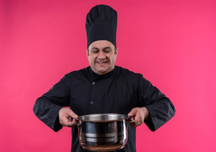 Photo gratuit souligne les hommes d'âge moyen cuisinier en uniforme de chef tenant une casserole lourde