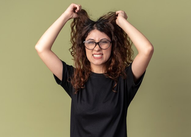 Photo gratuite a souligné la jeune jolie femme caucasienne portant des lunettes lui tirant les cheveux