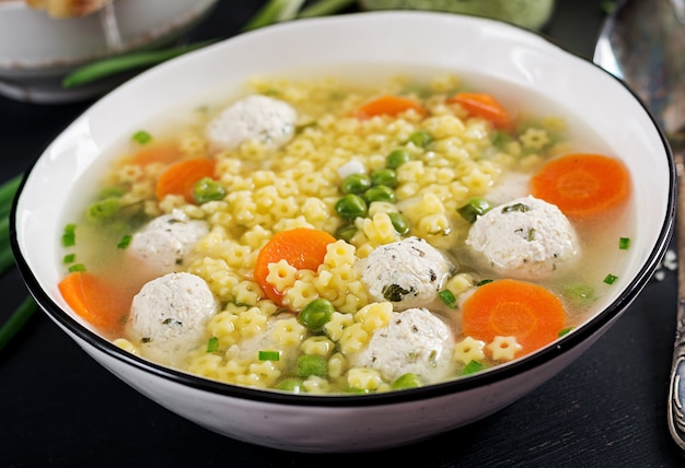 Soupe aux boulettes de viande italienne et pâtes sans gluten Stelline dans un bol sur le tableau noir. Soupe diététique. Menu bébé. Nourriture savoureuse.