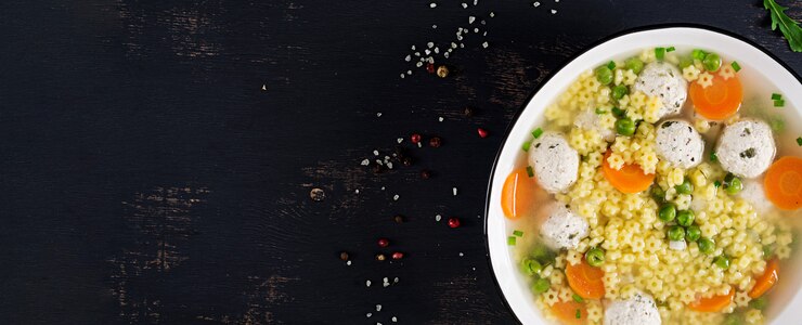 Photo gratuit soupe aux boulettes de viande italienne et pâtes sans gluten stelline dans un bol sur le tableau noir.
