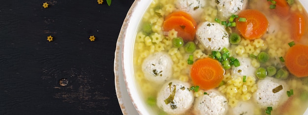 Soupe aux boulettes de viande italienne et pâtes Stelline dans un bol sur le tableau noir