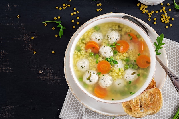 Soupe aux boulettes de viande italienne et pâtes Stelline dans un bol sur le tableau noir.