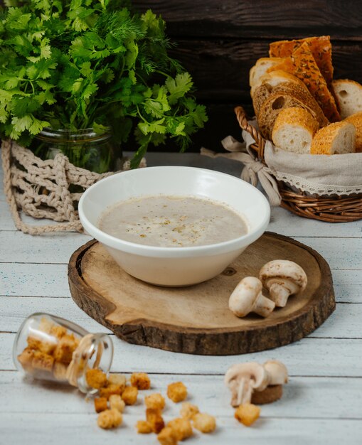 soupe aux champignons servie avec du pain farci sur une planche en bois