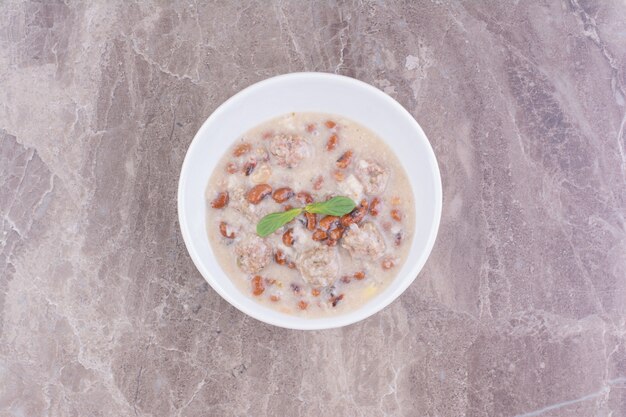 Soupe aux haricots bruns et spaghetties dans une tasse en céramique blanche