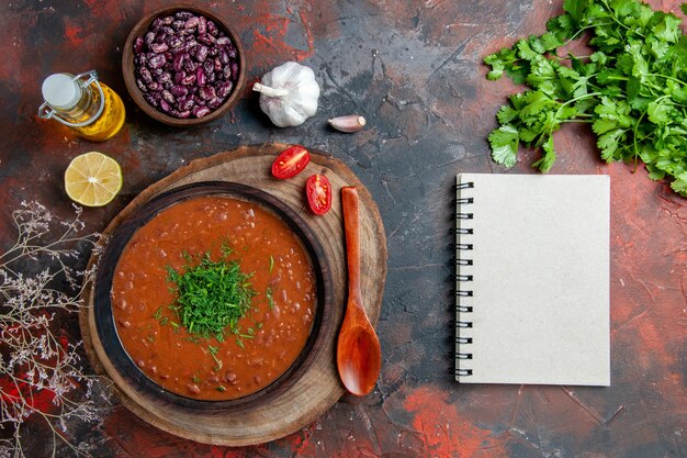 Soupe aux tomates classique dans un bol brun de haricots de bouteille d'huile et cuillère sur des images de table de couleurs mélangées