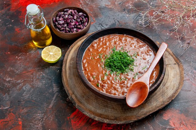 Soupe aux tomates classique dans un bol brun de haricots bouteille d'huile et cuillère sur table de couleurs mélangées