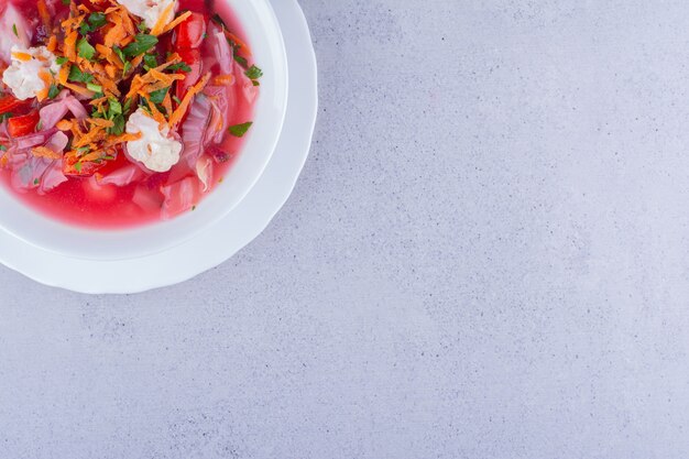 Soupe de bortsch avec garniture de carottes et de chou-fleur sur fond de marbre. photo de haute qualité