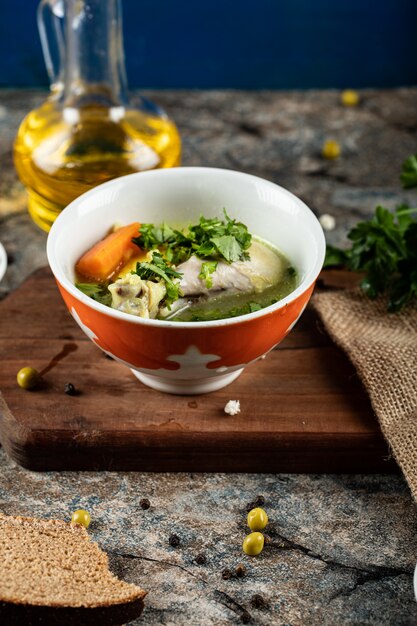 Soupe de bouillon aux herbes, pommes de terre et carottes dans un bol rouge