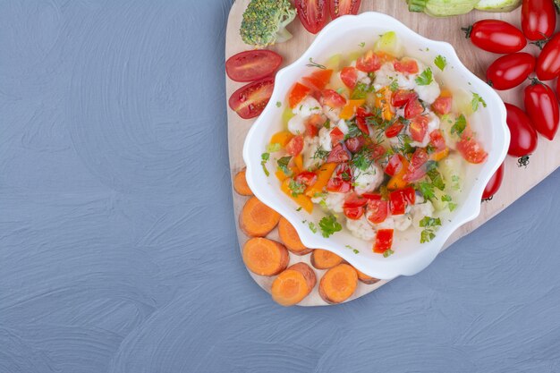 Soupe de bouillon de légumes dans un bol blanc avec des aliments hachés