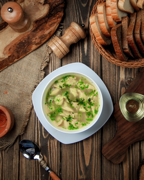 Soupe en bouillon avec des pâtes et des herbes à l'intérieur.