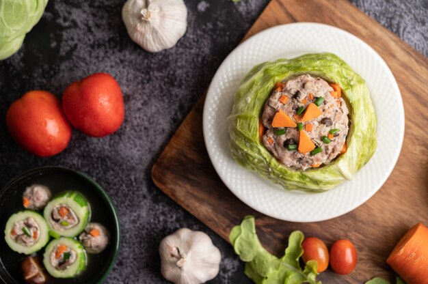 Soupe de chou de porc aux carottes, oignons verts hachés, concombre dans une assiette en bois sur une plaque en bois