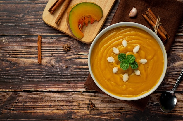 Soupe à la citrouille dans un bol blanc placé sur un plancher en bois