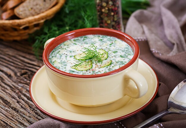 Soupe froide au yogourt d'été avec oeuf, concombre et aneth sur table en bois