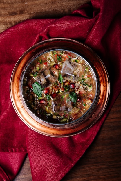 Soupe de haricots rouges aux herbes et épices dans une assiette en cuivre.