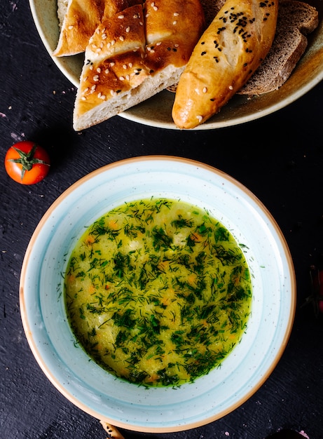 Soupe de légumes au bouillon avec herbes, tomates et pain.