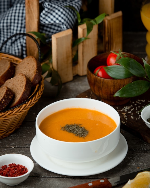 soupe de lentilles dans un bol blanc et une corbeille de pain